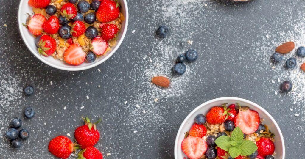 Top view of bowls filled with cereal, strawberries, and blueberries, perfect for a healthy breakfast.